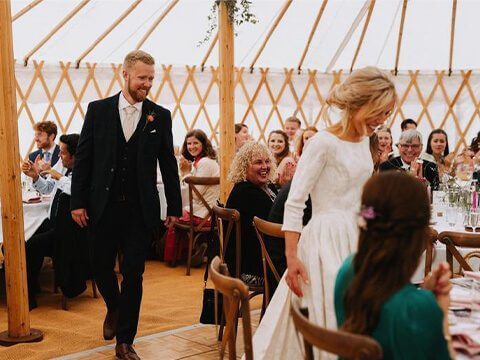 Bride and Groom walking around wedding yurt